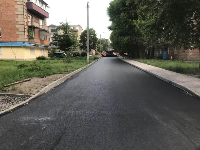 етап закатування двошарового асфальту між житловими будинками початок дороги з тратуаром між багатоквартирними житловими будинками вздовж вулиці попова
