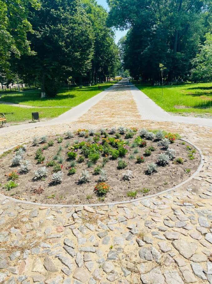 Початок парку Потоцьких з кільцевої різноманітної бруківки з клумбою Початок реконструйованого тратуару вздовж парку Потоцьких